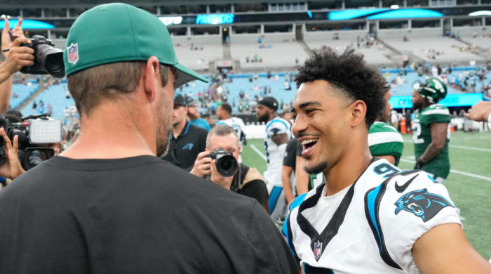Jets quarterback Aaron Rodgers talks to Panthers quarterback Bryce Young.